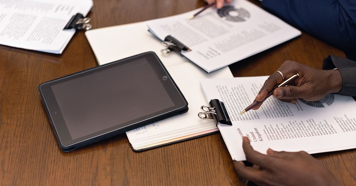 Documentos en papel y una tablet sobre un escritorio: el trabajo manual que reemplaza la automatización de procesos